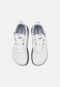 White athletic shoes with a textured upper, lace-up design, and contrasting dark sole. Features a cushioned insole. Light and breathable material.