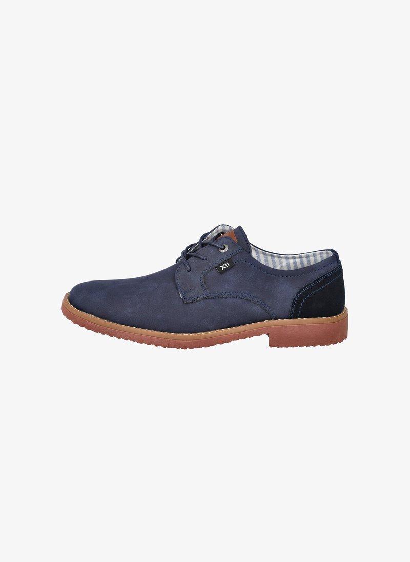 Zapato de ante azul marino con un acabado suave, punta redonda, diseño de cordones, suela marrón contrastante y forro de tela a cuadros.