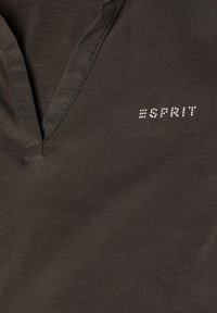 Tessuto verde scuro con una sottile texture a coste, con design a scollo a v e il nome del marchio "Esprit" in strass sul petto.