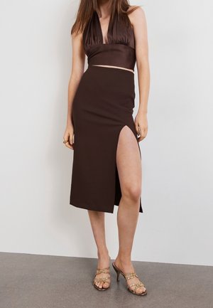 Ensemble marron deux pièces comprenant un haut sans manches à col halter et une jupe midi avec une fente haute, confectionné en tissu lisse.
