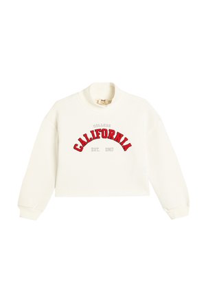 Sweatshirt cropped blanc avec un col rond côtelé. Présente un texte brodé rouge : "COLLEGE CALIFORNIA EST. 1987" dans un design courbé.