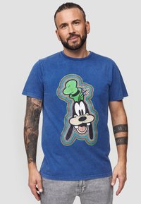 Blauwe katoenen t-shirt met een grote graphic van Goofy omlijnd met meerkleurige strepen. Korte mouwen en een ronde hals.
