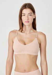 Sujeción seamless de color rosa claro con un diseño de escote en V, tirantes ajustables y una tela suave y elástica. Estilo simple y minimalista.