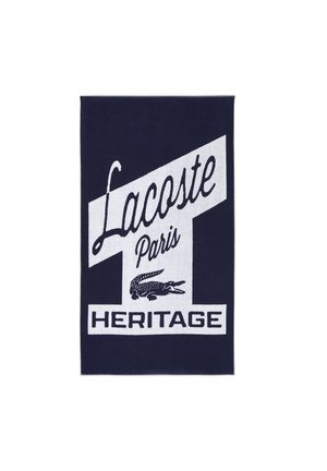 Serviette bleu foncé avec texte blanc « Lacoste Paris Heritage » et un logo de crocodile au centre.