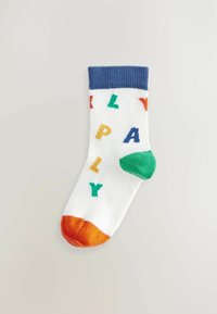 Weißer Socken mit blauem Rippbündchen, orangefarbener Spitze, grünem Absatz und mehrfarbigen Buchstaben, die "PLAY" in verschiedenen Schriftarten über den Körper schreiben.