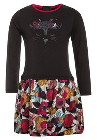 Černé šaty s dlouhým rukávem a výšivkou kočičí tváře, s barevným květinovým sukní s různorodým vzorem a nabíranou texturou.