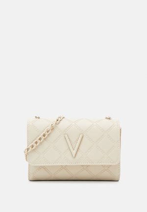 Sac bandoulière matelassé beige avec bandoulière chaîne et logo en forme de V bien visible sur le rabat avant.