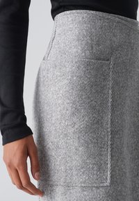 Grau gestreifte Rock aus strukturiertem Stoff, mit großer Seitentasche und hoher Taille. Der Stoff hat eine weiche, gewebte Optik.