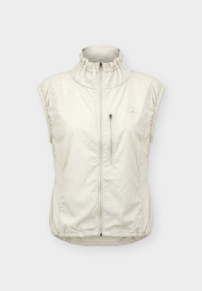 Αμάνικο ανοιχτό μπεζ γιλέκο με φερμουάρ, υψηλό ραβδωτό γιακά, μπροστινή τσέπη στο στήθος με φερμουάρ και ελαστικό τελείωμα και ανοίγματα για τα χέρια.