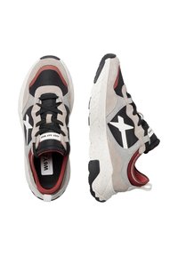 Sneakers chunky in beige, nero e rosso. Presentano materiali in suede e mesh, un design a croce bianco, una suola spessa e testurizzata, e accenti a contrasto.