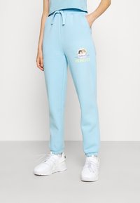 Ljusblå sweatshirtbyxor tillverkade av mjukt tyg, med elastisk midja och snörning samt muddar vid anklarna. Inkluderar en pastellfärgad grafisk design.