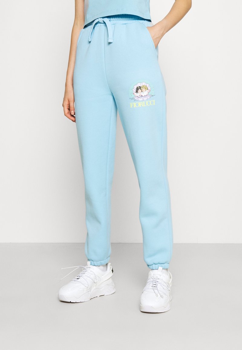 Ljusblå sweatshirtbyxor tillverkade av mjukt tyg, med elastisk midja och snörning samt muddar vid anklarna. Inkluderar en pastellfärgad grafisk design.