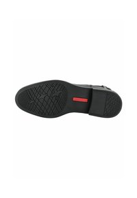 Semelle de chaussure noire avec surface en caoutchouc texturé, dotée d'un motif de grip et d'un détail de logo rouge, conçue pour la traction et la durabilité.