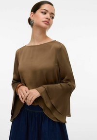 Brun, genomskinlig långärmad topp med utsvängda ärmar och rund halsringning, kombinerad med en mörk denimkjol. Slät textur och lätt design.