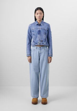 Cropped blue denim jacket with a collar and zipper, paired with loose light blue denim pants and tan platform boots.