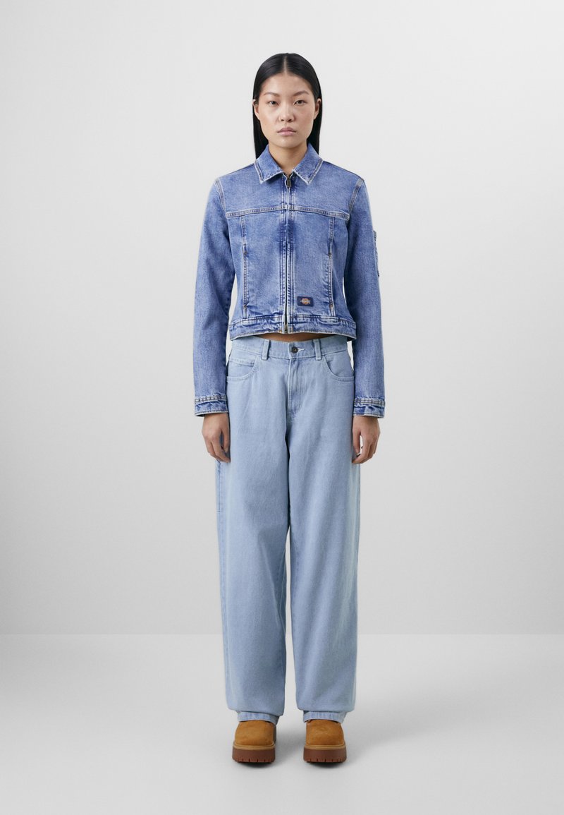 Beskyttende blå denimjakke med krage og glidelås, kombinert med løse lyseblå denimbukser og beige plattformstøvler.