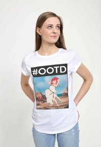 Bílý bavlněný tričko s potiskem grafiky postavy s červenými vlasy, oblečené v bílých šatech, obklopené plážovou scenérií.