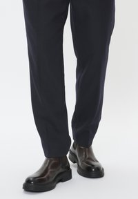 Pruunid nahast chelsea saapad läikiva viimistlusega, omavahel koos tumedad meresinised püksid, millel on täpselt sobiv lõige ja tekstuurne kangas.