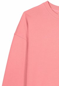 Felpa rosa a maniche lunghe con scollo tondo, cuciture delle spalle scese e collo a coste, mostrata su sfondo bianco.