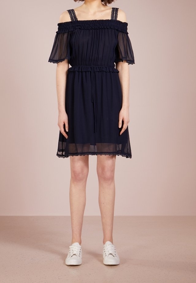 Námořnické off-shoulder šaty s elastickým smockováním, průhlednými krátkými rukávy a krajkovým lemem. Stylizováno s bílými teniskami pro kontrast.