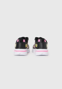 Black sneakers with pink accents, yellow flower patterns on sides, cushioned white sole, and a smooth texture. Rear view shown.
