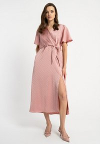 Różowa sukienka o fasonie kopertowym, wykonana z gładkiego materiału w delikatny wzór kropek, z krótkimi rękawami, wiązaniem w talii i rozcięciem z boku. W komplecie z pasującymi szpilkami.