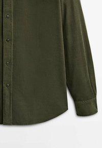 Chemise en velours côtelé à manches longues de couleur vert olive foncé, avec des manches à revers et un ourlet arrondi, sur fond blanc.