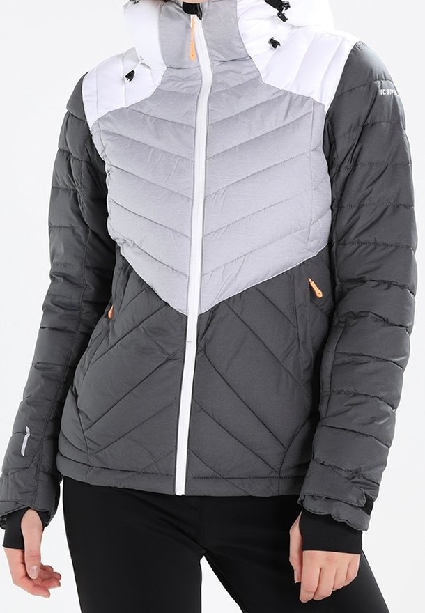 Grå och ljusgrå quiltad jacka med vit huva, med en asymmetrisk chevrondesign, orange detaljer och framzipning.