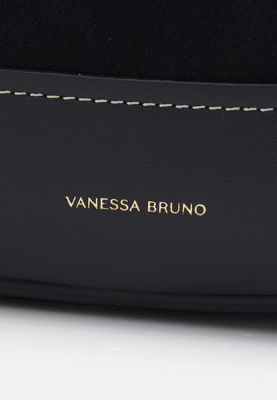 Black leather bag featuring a smooth texture, contrasting stitching, and a gold embossed logo "VANESSA BRUNO" on the front.