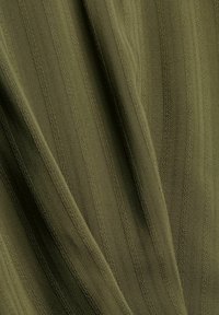 Tissu texturé vert olive avec des rayures verticales, présentant des lignes en relief et une finition lisse. Matériau doux et souple avec des détails subtils.