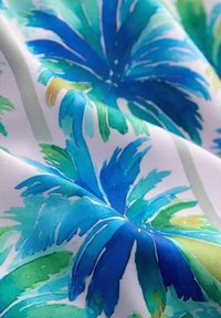 Tissu présentant de grandes feuilles tropicales abstraites dans des tons de bleu et de vert sur un fond blanc, avec une texture lisse et douce.