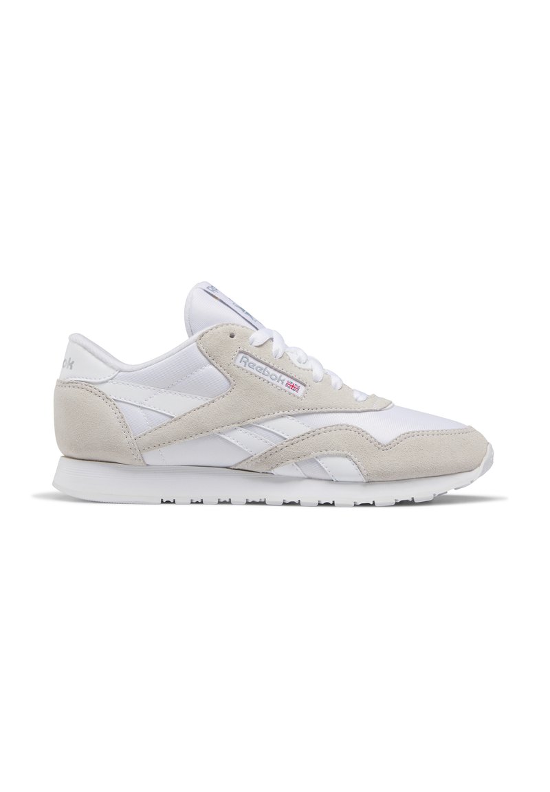Valged ja beežid Reeboki sneakersuud koos sametiste ülekatetega, paeltega kinnitamise süsteem ja kummist tald, näidatud külgprofiilis valgel taustal.