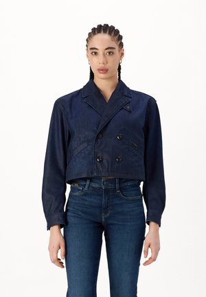 Jachetă din denim croită, de culoare bleu marin, cu un design cu două rânduri de nasturi, două buzunare frontale și guler cu colțuri. Textură netedă și nasturi clasici.