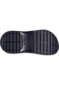 Suela de zapato de goma negra con una superficie texturizada, que presenta ranuras verticales y horizontales para tracción y estabilidad.