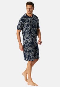 Námořnický bavlněný loungewear set obsahující vzorované tričko s krátkým rukávem a odpovídající šortky s kruhovými vzory a hvězdami.