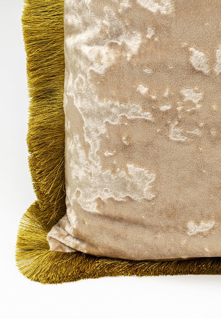 Cuscino con un morbido tessuto beige a trama apparentemente sottile, bordato da una vivace rifinitura verde con frange. Forma quadrata, design morbido.