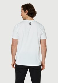 Vit bomullst-shirt med korta ärmar, med rund halsringning och en liten svart avokado-logotyp på baksidan. Strukturerad tygkvalitet, avslappnad passform.