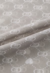 Tessuto grigio con una texture lucida, caratterizzato da un motivo ripetuto di forme interconnesse e cuori bianchi. Aspetto morbido e liscio.