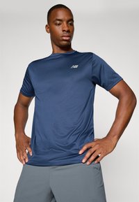 Marineblaue, kurzärmlige Sport-T-Shirt aus glattem, feuchtigkeitstransportierendem Material mit einer subtilen gestreiften Textur und einem kleinen Logo auf der Brust.