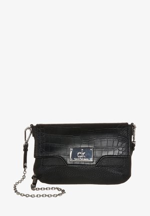 Czarna torebka na ramię Calvin Klein z teksturowaną klapką, srebrną plakietką z logo oraz łańcuszkowym paskiem na białym tle.