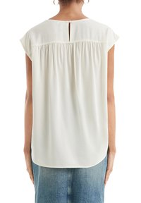Blusa bianca a maniche corte con un sottile plissè sul retro e chiusura a bottone sul collo. Tessuto leggero e liscio; orlo arrotondato.