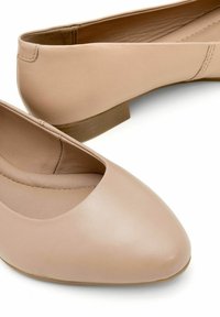 Beżowe skórzane baleriny z okrągłym czubkiem, niskim obcasem i przeszyciem wzdłuż boków, charakteryzujące się gładką teksturą i czystym designem.