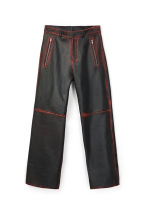 Pantalon en cuir synthétique noir avec des détails rouges usés, poches zippées à l'avant, passants pour ceinture et jambes larges.