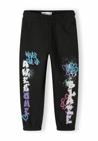 Zwarte sweatpants met een elastische tailleband, versierd met graffiti-achtige tekst in blauw, paars en roze, samen met spetteraccenten.