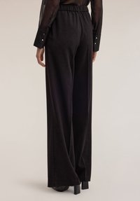 Luchtige zwarte broek gemaakt van zachte stof met een elastische tailleband. Heeft minimale details en wijde pijpen. Geschikt voor verschillende gelegenheden.