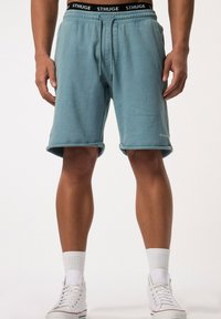 Lichtblauwe katoenen shorts met een elastische tailleband, voorzien van zwarte trekkoorden en een logo. Opgerolde zoom en zijzakken.