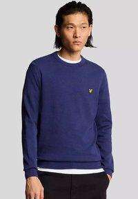 Maglione blu navy realizzato in materiale morbido, con scollo rotondo e polsini a coste, decorato con un piccolo logo giallo sul petto.