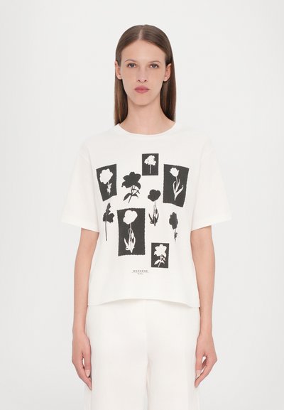 White, short-sleeve T-shirt featuring black floral prints in various shapes and sizes. Soft cotton fabric with a relaxed fit.
