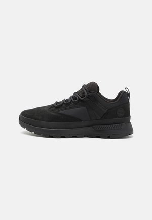 Scarpa atletica nera con superiore in suede e sintetico, caratterizzata da un design con lacci, collo imbottito e suola in gomma testurizzata.