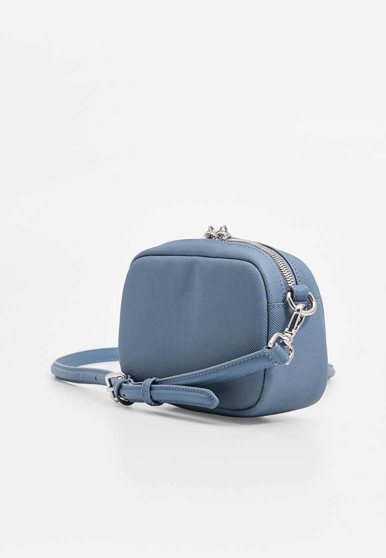 Sacoche croisée synthétique bleue de forme carrée, surface texturée, fermeture éclair en métal argenté et bandoulière réglable.